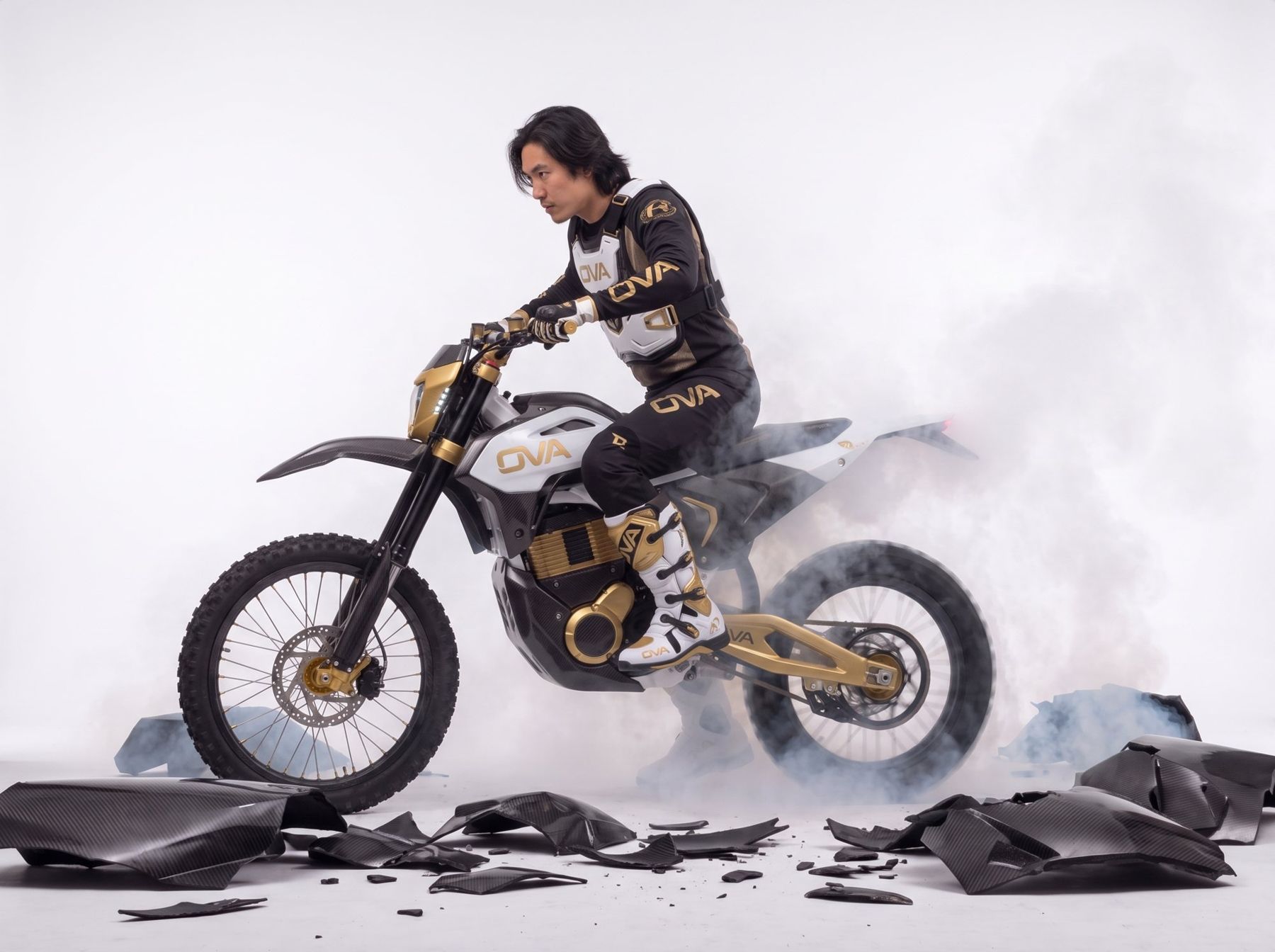 OVA MXギアでオフロードバイクに乗るライダー、スモークとカーボンの破片